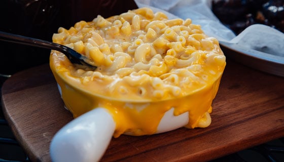macaroni and cheese in crock with cheese flowing over Brothers BBQ Colorado